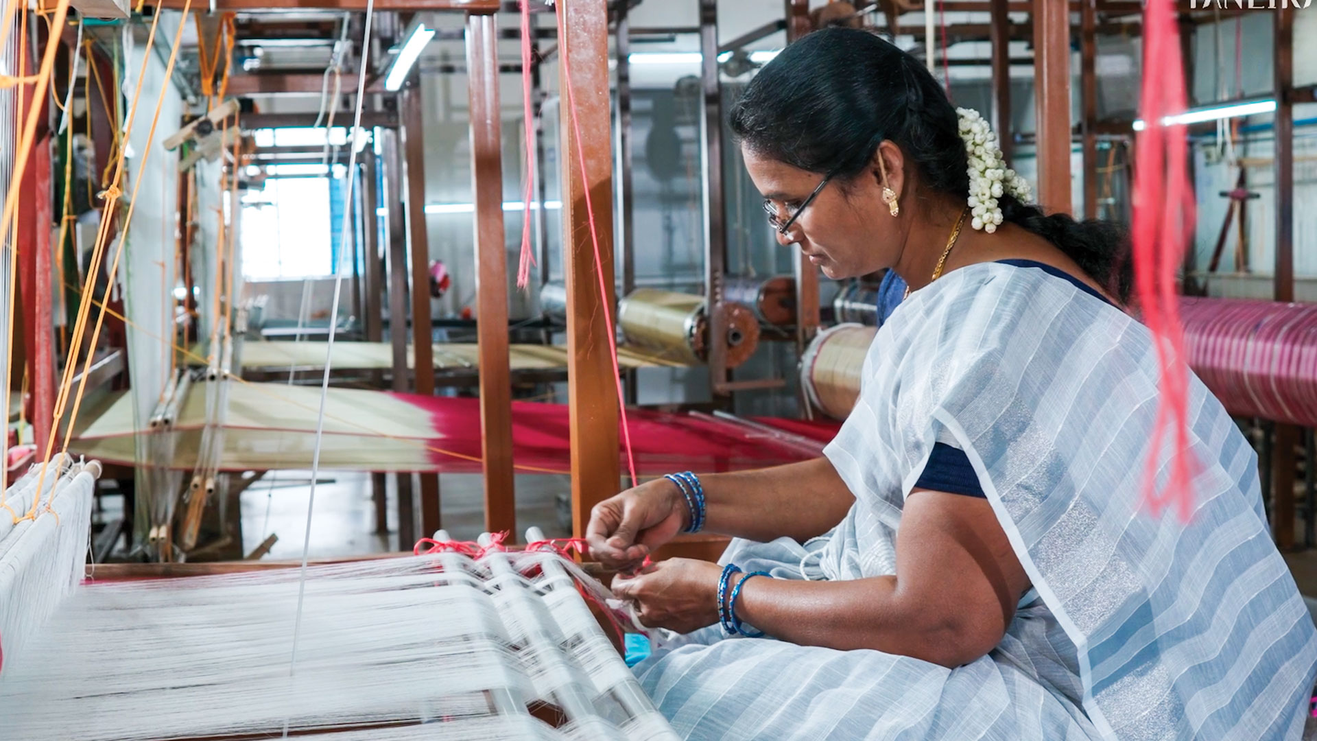 A woman handcrafting a design into a saree